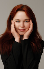 Beauty with freckles smiling. Portrait of beautiful woman with redhair. Confident female wearing black blazer while posing at dark background