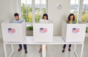Group of young confident American citizens voters standing in a row at vote center with USA flags...