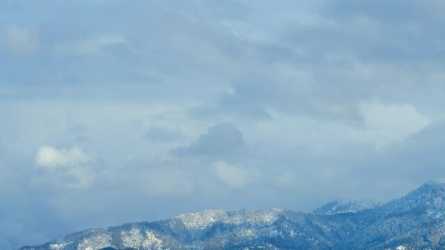 Blue Sky And White Clouds. Snow-Covered Mountain Peaks Against A Blue Sky With Clouds. Timelapse.