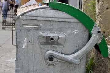 Aluminum trash can with green lid, close-up lid mechanism