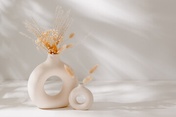 Home interior still life composition. Ceramic vase set with dry flowers and pampas on white table...