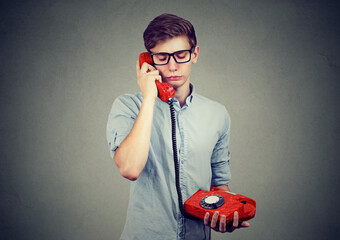 Portrait of a sad young man talking on a telephone  - 788070804