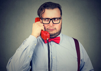 Closeup portrait of a serious grumpy looking businessman talking on telephone 