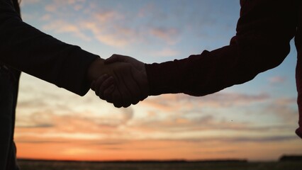Handshake at sunset, silhouette in park field. Making deal teamwork cooperation successful joint...