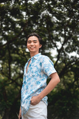 Young man in tropical shirt smiling in a lush forest background