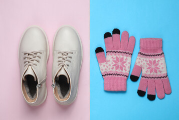 Women's white leather winter boots with gloves on a blue-pink background. Top view