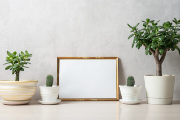 Template with photo frame on a wooden table. Houseplants in a pots.