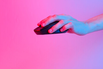 Hand holding Wireless black pc mouse in blue-pink gradient neon light