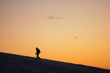 Silhouette picture of a hiker during a colorful winter sunset in the Orobie Alps, Northern Italy