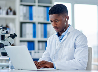 Science, man and laptop in lab with typing for medical research, microscopic experiment or DNA testing with earphones. Scientist, african expert or serious for gene editing or healthcare breakthrough
