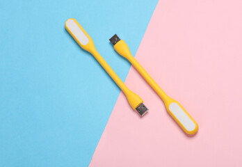 Flexible yellow USB lamps on blue-pink background. Top view