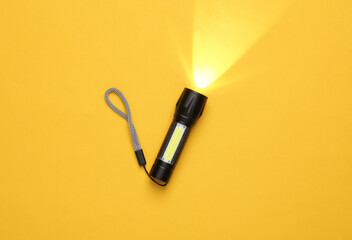 Pocket flashlight on yellow background.