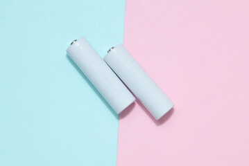 White aa batteries or accumulators on a blue-pink background