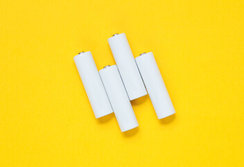 White blank aa batteries or accumulators on a yellow background. Mockup for design