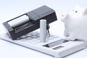 Calculator with AA battery and piggy bank on a white background