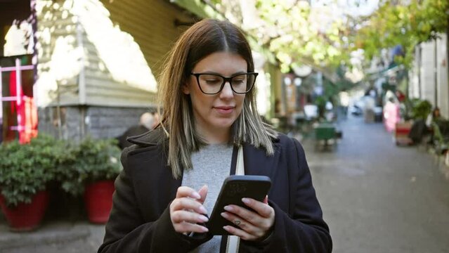 Smiling young woman using smartphone on a sunny istanbul street, depicting urban travel and connectivity.