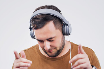 Headphones, dance or man streaming music in studio for wellness on grey background to relax. Model,...