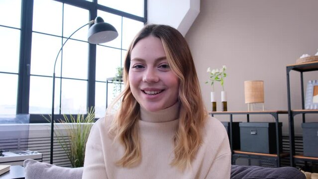 Joyful Caucasian woman talking with friends or family, farewell during video call, saying goodbye and waving hand at home. Female vlogger recording video for social video.