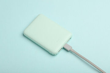 Plastic power bank with cable on blue pastel background