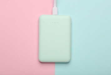 Plastic power bank mint green color on pink blue pastel background. Top view
