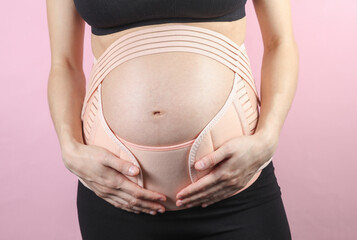 Young Pregnant woman with orthopedic belt for back and belly support. Bandage for pregnant women....