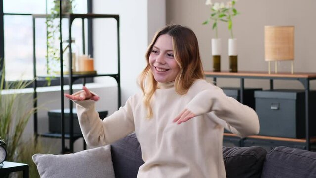 Happy Caucasian young woman dancing at home during weekend leisure time, resting on sofa, listening music. Having fun during free time.