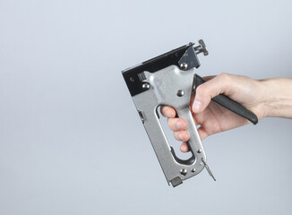 Construction stapler in hand on gray background