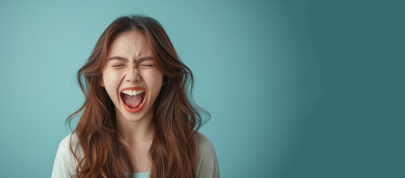 A woman with long hair is screaming and her mouth is open. Concept of anger and frustration. a young woman yelling in simple background, consumer culture critique. strong facial expression