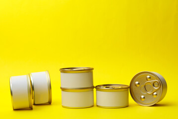 Tin cans of canned food with white labels on yellow background, mockup for your design - obrazy, fototapety, plakaty