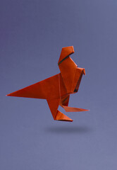 Red Origami dinosaur levitating on a purple background