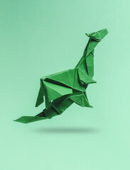 Green Origami dragon levitating on pastel background