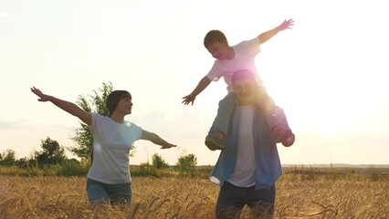 Mother father and son playing flying fantasy at sunset bright sun dry wheat field. Happy family...