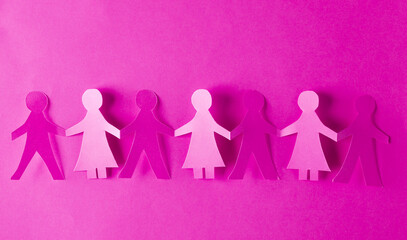 Paper cut chain of people holding hands on pink background. Unity concept