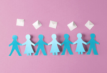 Paper cut chain of people holding hands and envelopes on pink background.