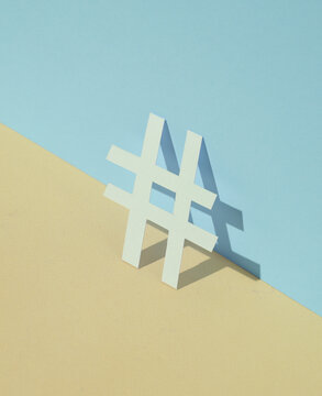 Paper-cut hashtag on blue-yellow pastel background