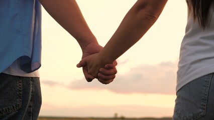 Couple man and woman taking hands to each other at sunset sky summer meadow romantic date closeup....
