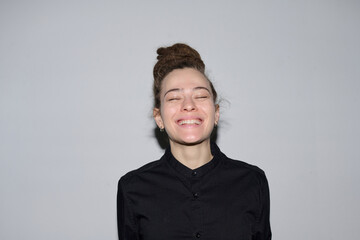 Minimal portrait of Caucasian woman with dreadlocks in bun hairstyle and candid big smile standing...