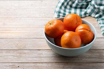 Fresh tangerines in green bowl on wooden table. Copy space - 788106418