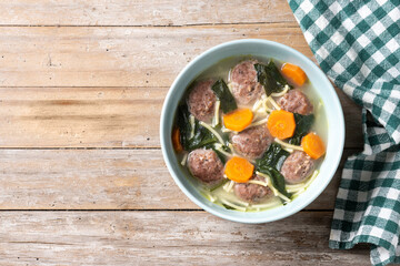 Italian Wedding Soup with meatballs and spinach on wooden table. Top view. Copy space