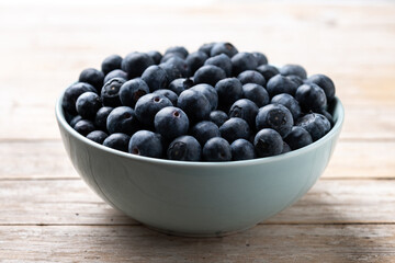 Blueberries in green bowl on wooden table - 788106471