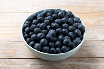 Blueberries in green bowl on wooden table - 788106473