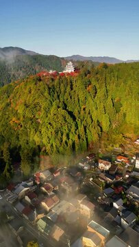 Aerial view of Gujo Hachiman Castle surrounded by fall foliage and mist, Gujo, Gifu, Japan.