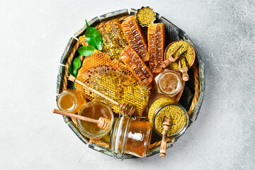 Beekeeping products in a round wooden box. Set Honey in honeycombs, flower bee pollen, and honey. Top view.