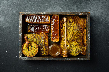 Set of honey, bee products and honeycomb honey. On a dark background. Top view. In a wooden box.
