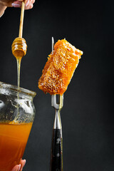 A honey stick with honey in a woman's hands watering the honeycombs. Honey and beekeeping products.
