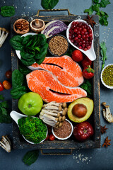 Healthy food background. Healthy food clean eating selection in wooden box: fish, superfood, fruits and berries, nuts and vegetables. On a gray stone background.