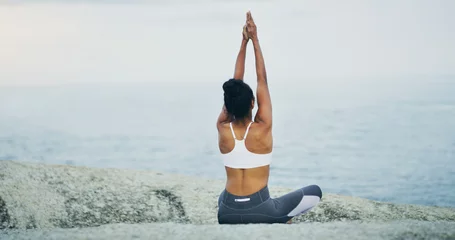  Beach, yoga or woman stretching arms in lotus meditation for peace or mindfulness in outdoor nature to relax. Chakra, calm or back of girl on rock at sea or ocean for awareness or balance in pilates © peopleimages.com