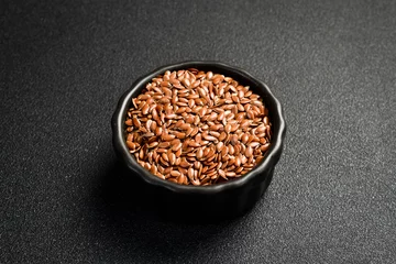  Close-up of flax seeds in a ceramic bowl. Superfood On a dark concrete background. © Yaruniv-Studio
