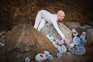 Young hairless girl with alopecia in white futuristic costume reaches hand for surreal landscape...