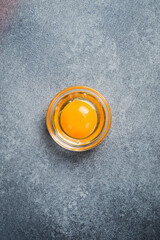 Close-up of the yolk of a chicken egg. On a gray stone background. Top view.